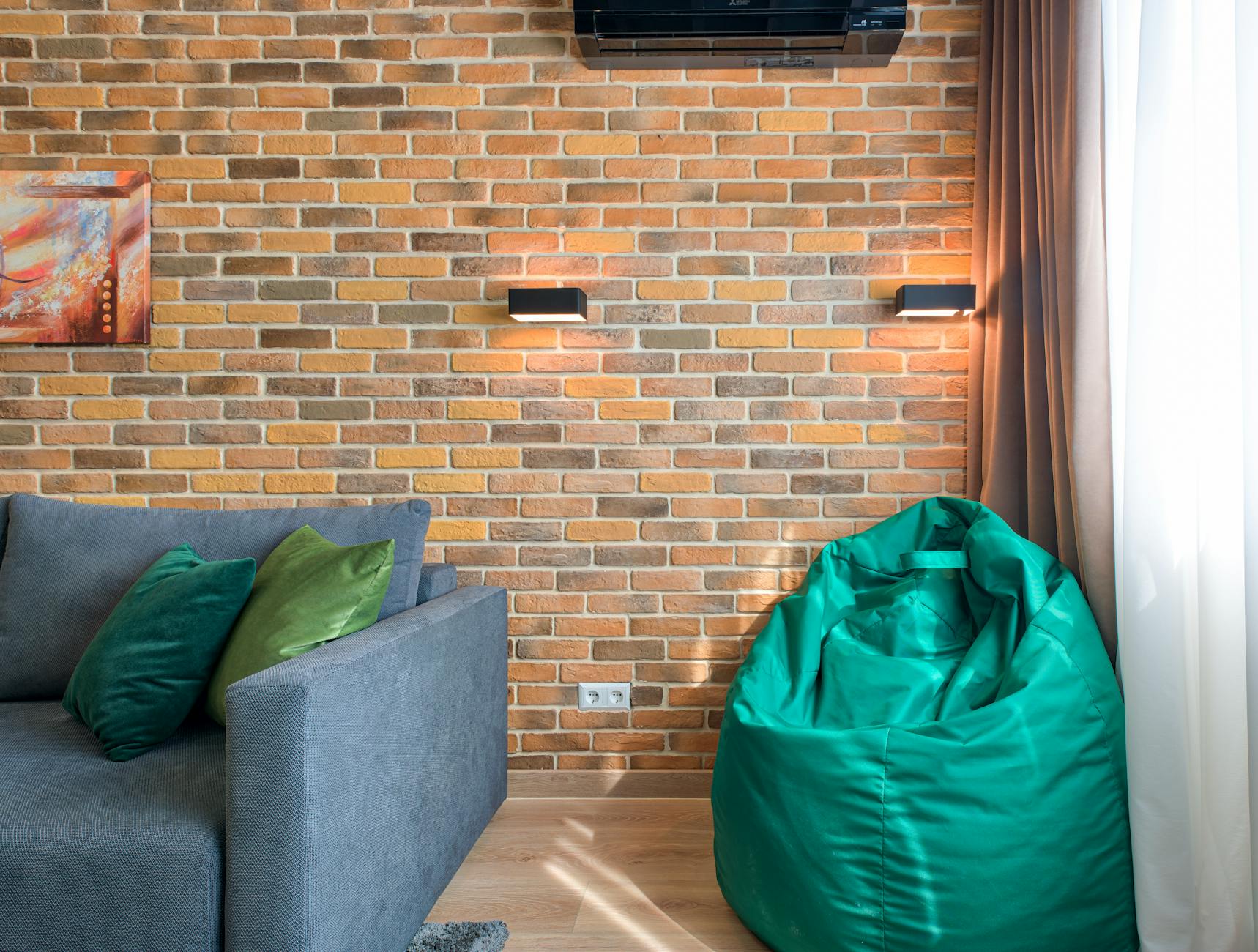 green bean bag near brown brick wall